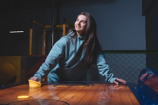 Beautiful sports girl plays air hockey in the entertainment center