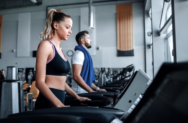 Beautiful sports people work on the treadmill in the gym