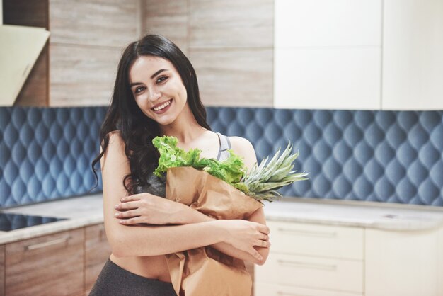 A beautiful sports woman with fresh fruits and vegetables in the kitchen