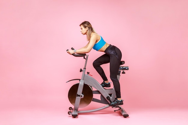 Beautiful sportswoman cycling a bike at home cardio training exercising legs