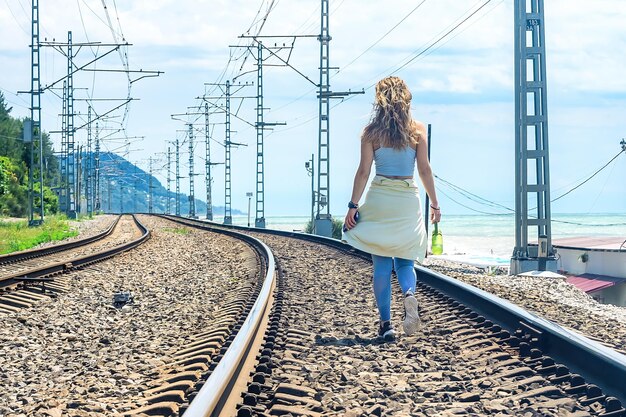 Beautiful sportswoman with a bottle of water stands on the railroad and looks into the distance