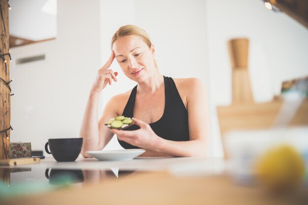 Beautiful sporty fit young pregnant woman having a healthy snack in home kitchen Healty lifestyle concept