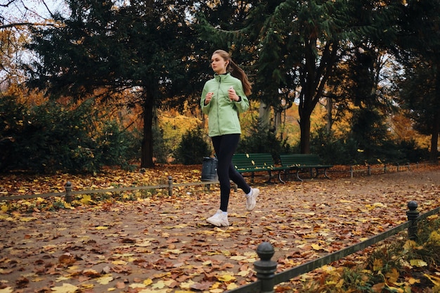 Beautiful sporty girl thoughtfully running around cozy autumn park alone