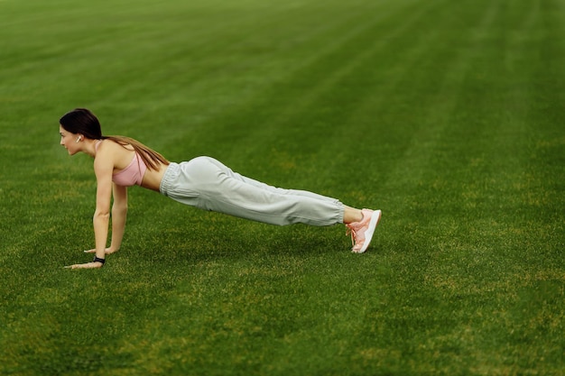 Beautiful sporty lady doing stretching at the stadium practice flexibility athletic woman training