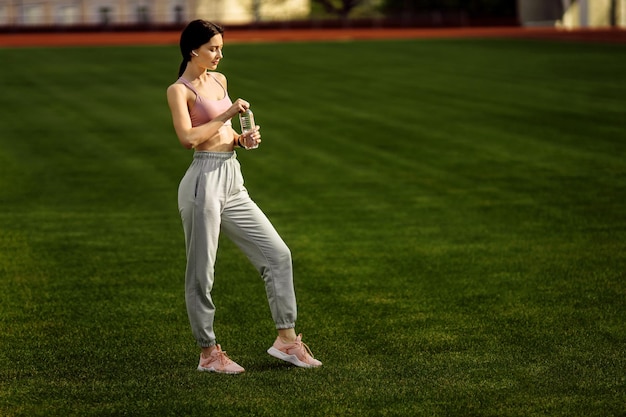 Beautiful sporty lady doing stretching at the stadium practice flexibility athletic woman training