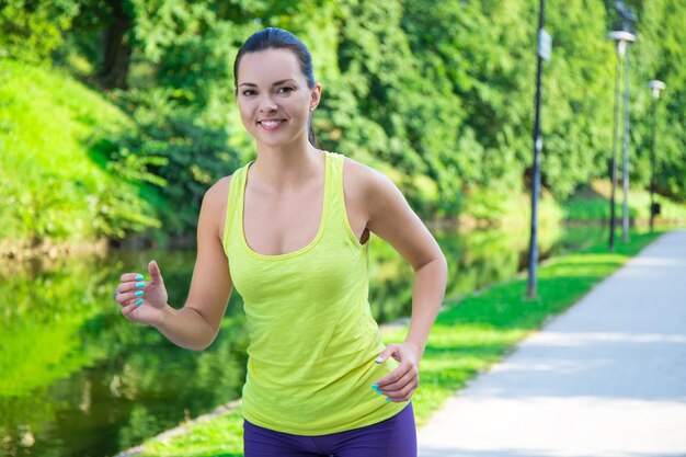 Beautiful sporty slim woman running in summer park