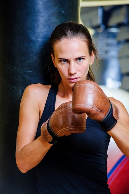 Photo beautiful sporty woman boxing with red punching bag at gym