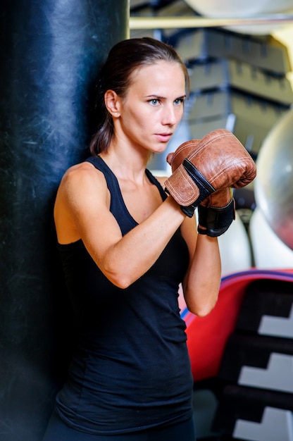 Beautiful sporty woman boxing with red punching bag at gym