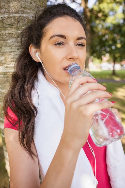 Photo beautiful sporty woman leaning against a tree