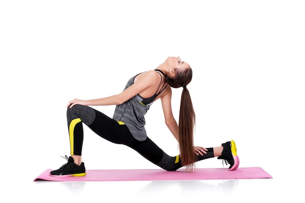 beautiful sporty woman in sportswear does exercises on fitness Mat isolated on white background. stretching