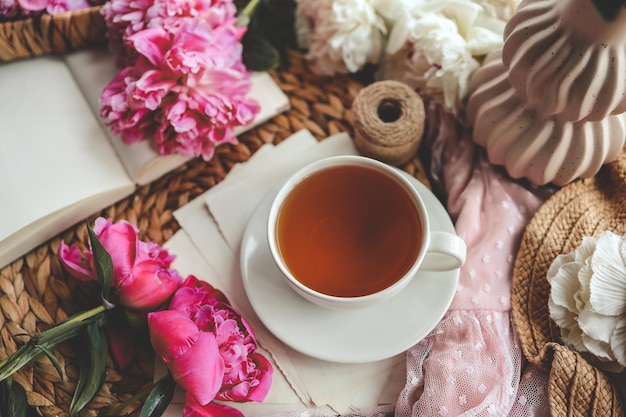 Beautiful spring composition good morning concept Cup of tea peonies and open book