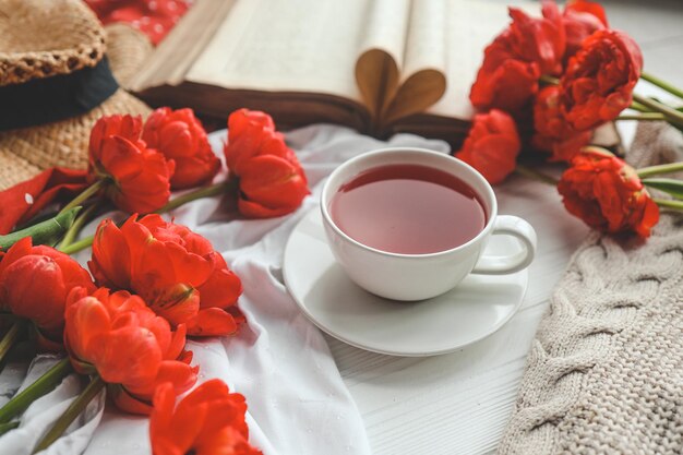 Beautiful spring composition good morning concept Cup of tea peonies open old book