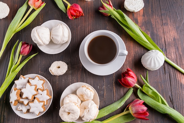 beautiful spring tulip flowers and cup of coffee on rustic wooden background