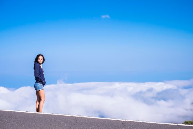 Beautiful standing young female caucasian people at the side of the road with amazing and blue cloudy background travel and enjoy the nature concept for people