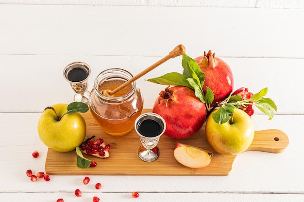 잘 익은 석류와 사과가 있는 아름다운 정물화 와인 한 잔과 꿀 한 그릇 흰색 배경 Rosh Hashanah의 개념