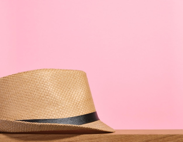 A beautiful straw garden hat on a pink background Home and garden concept