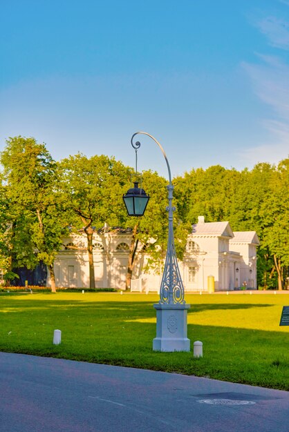 Красивый уличный фонарь на фоне зеленого луга и голубого неба в Елагинском парке Санкт-Петербурга