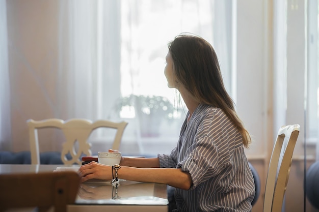 Beautiful student girl reading a book during breakfast at home