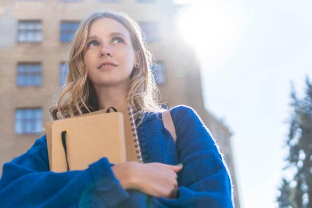Foto bella studentessa con quaderni al petto sullo sfondo dell'università