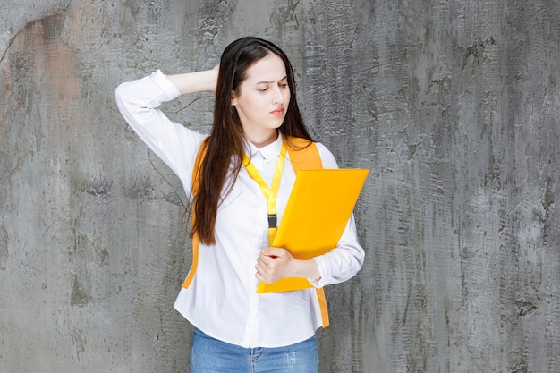 Beautiful student in white shirt holding book with tired expression. High quality photo