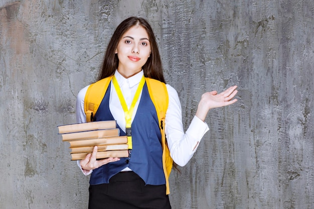 Bella studentessa con libri in piedi e in posa. foto di alta qualità