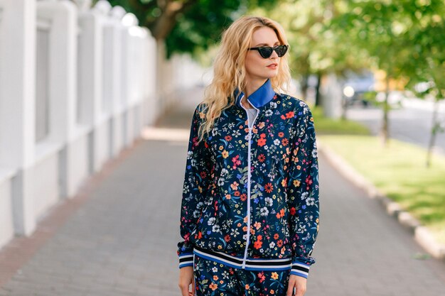 Beautiful stylish blonde model in colored suit posing in the street