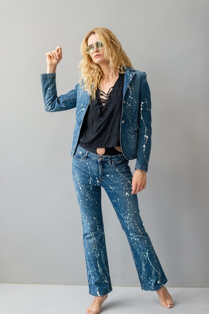 Beautiful stylish blonde model in jeans suit posing in studio