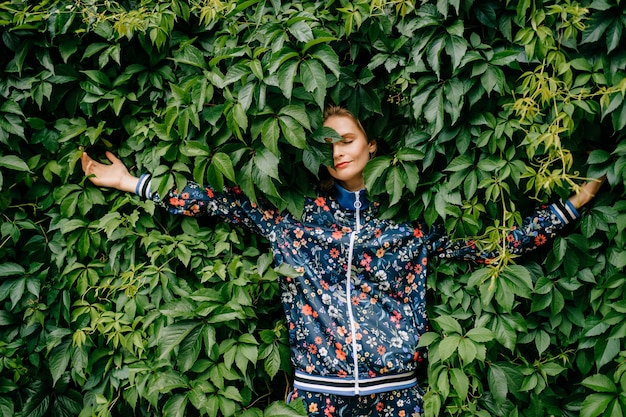 Beautiful stylish blonde model posing in green bushes