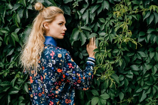 Beautiful stylish blonde model posing in green bushes