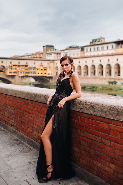 검은 드레스를 입은 아름다운 세련된 신부가 이탈리아의 옛 도시에있는 검은 드레스를 입은 모델 피렌체를 안내합니다.
