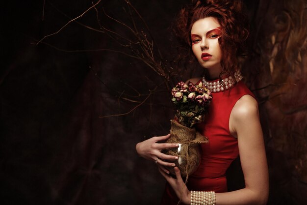 Beautiful stylish brunette in red dress holding a bouquet of dri