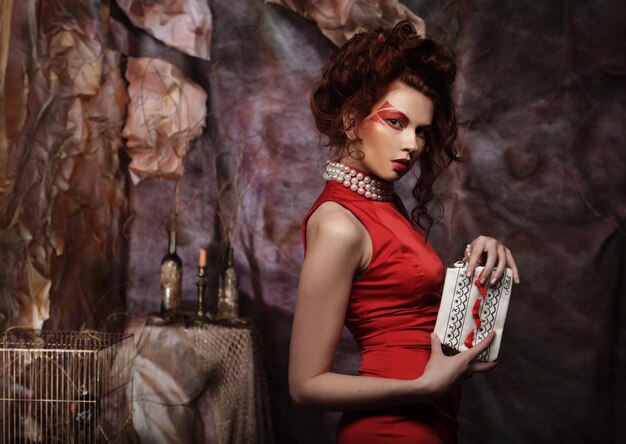 Photo beautiful stylish brunette in a red dress is holding a handbag