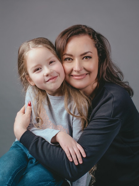 beautiful stylish brunette woman with adorable daughter indoor