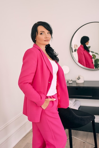 Photo beautiful stylish confident brunette in modern interior by the mirror in trendy fuchsia suit