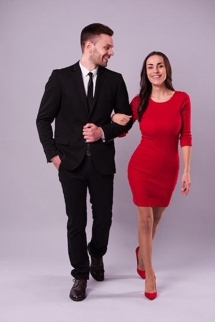 Beautiful stylish and elegant couple in suit and dress are hugging, have a fun and posing isolated in studio. Holidays and events. St Valentine's day. Day of lovers