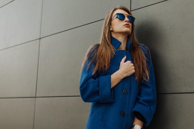 A beautiful stylish fashionable woman in a fur coat hat and glasses posing on the street