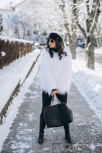 A beautiful, stylish, fashionable woman in a fur coat, hat and glasses