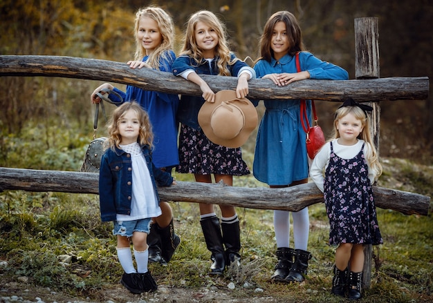 Beautiful stylish girl friends near a mountain lake in the forest, denim style. The idea and concept of a happy childhood, sisterhood and unity with nature