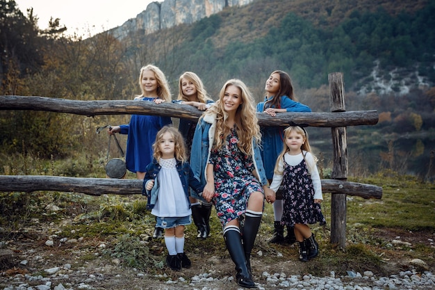 Beautiful stylish girl friends near a mountain lake in the forest, denim style. The idea and concept of a happy childhood, sisterhood and unity with nature