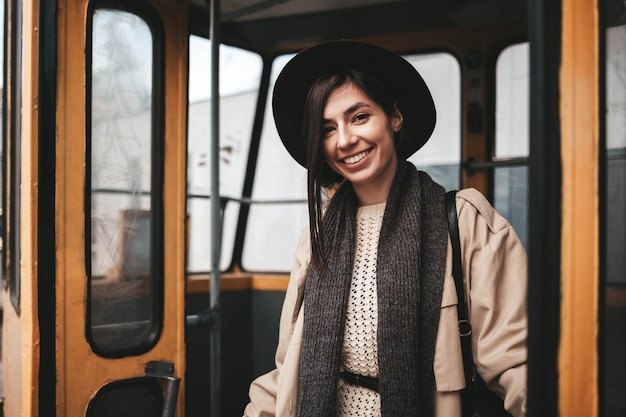 Beautiful stylish girl in hat gets off the tram