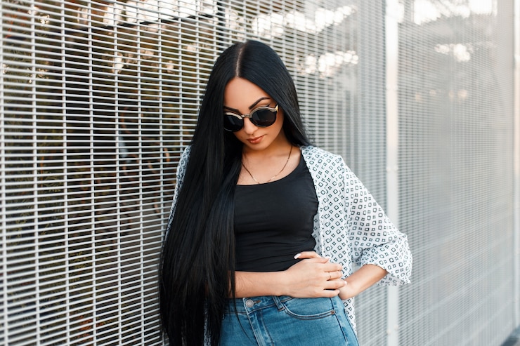 Photo beautiful stylish hipster woman in fashionable clothes with round sunglasses near the white wall of a grid