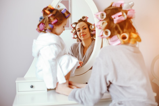 A beautiful and stylish mom makes her hairstyle for her and her little daughter