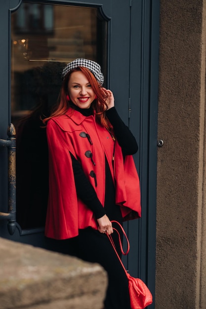 A beautiful stylish woman dressed in an elegant red coat with a stylish red handbag in the autumn city