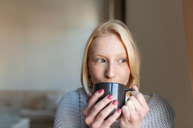 Beautiful stylish woman sitting at home thinking romantic\
melancholy mood wearing knitted sweater