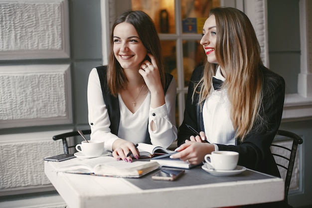 beautiful and stylish young businesswomen sitting in a cafe and working