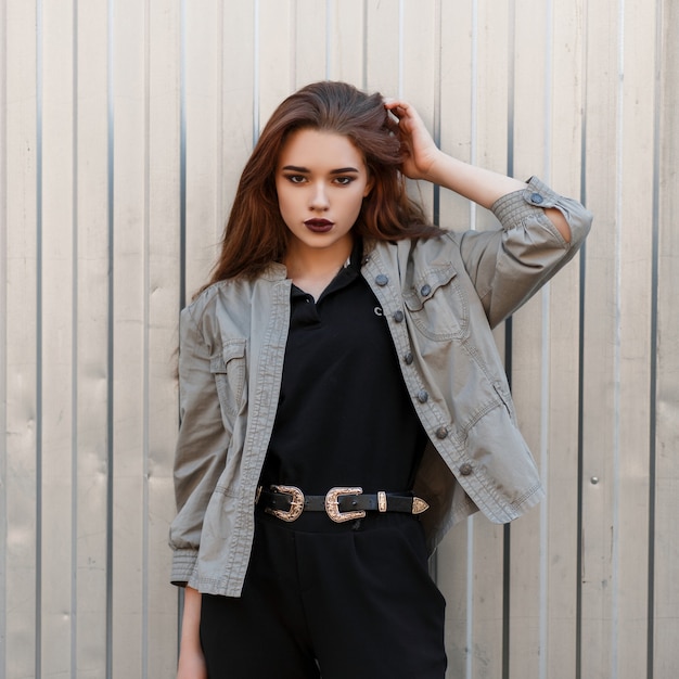 Beautiful stylish young model woman in fashionable clothes posing near a metal wall