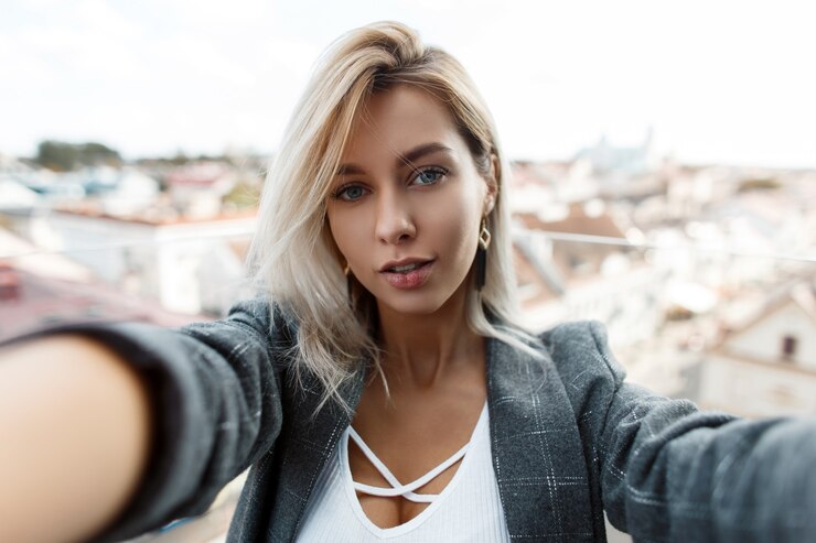 一位穿着复古时尚外套的漂亮时髦的年轻女人正在城市屋顶上旅行和拍照.