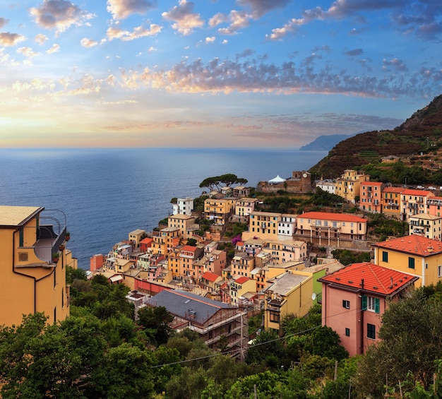 이탈리아 리구리아(Liguria)에 있는 친퀘테레 국립공원(Cinque Terre National Park)의 유명한 5개 마을 중 하나인 아름다운 여름 리오마조레(Riomaggiore)는 리구리아 바다와 깎아지른 절벽 위의 땅 사이에 매달려 있습니다.