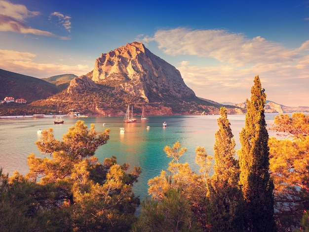 Bellissimo tramonto estivo al mare con montagne e alberi