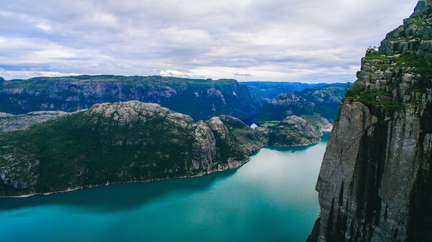 Красивый летний яркий вид на знаменитое норвежское туристическое место - тролльтунга, язык троллей с озером и горами, Норвегия, Одда.
